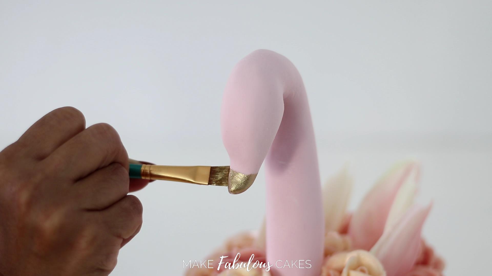 painting the beak of the swan cake with gold