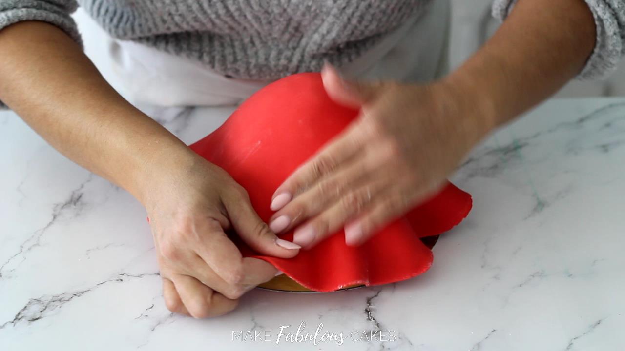 covering mushroom cake top with red fondant