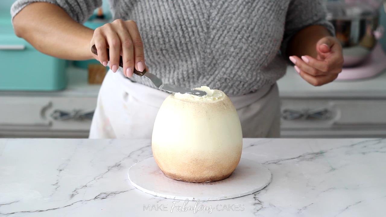 spread buttercream on top of mushroom cake with small offset spatula