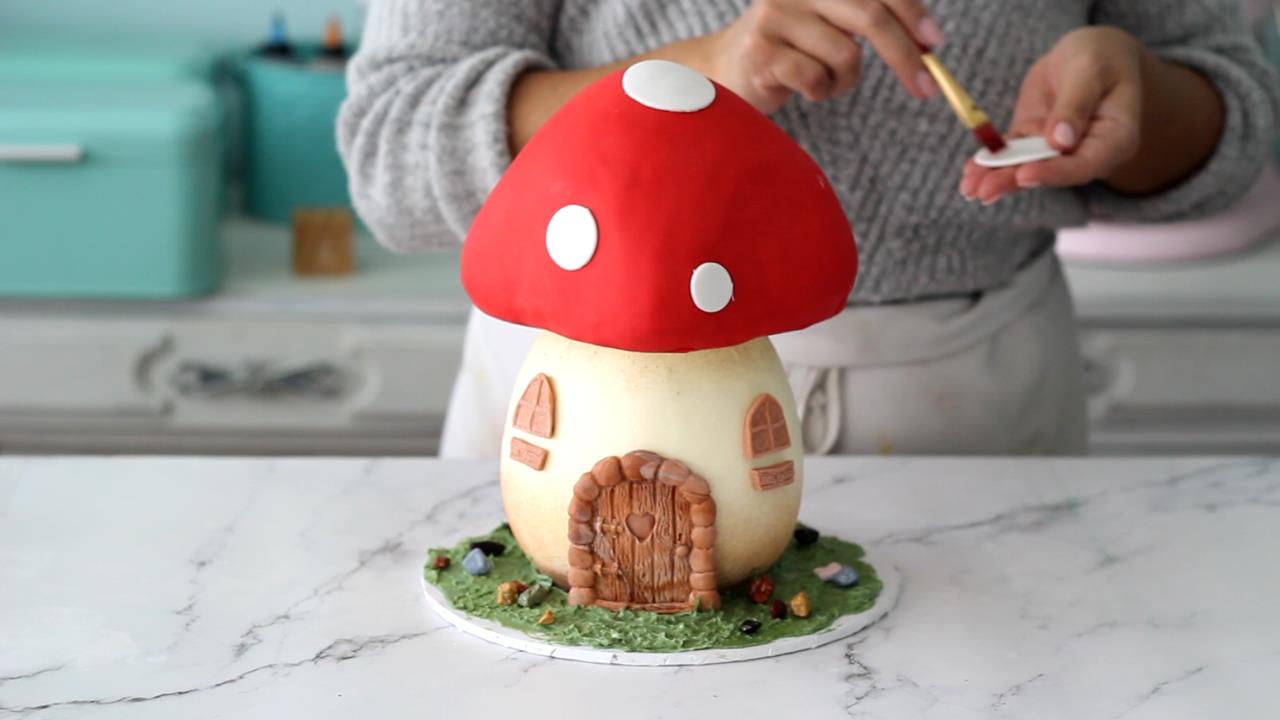 adding white fondant circles on top of the mushroom cake