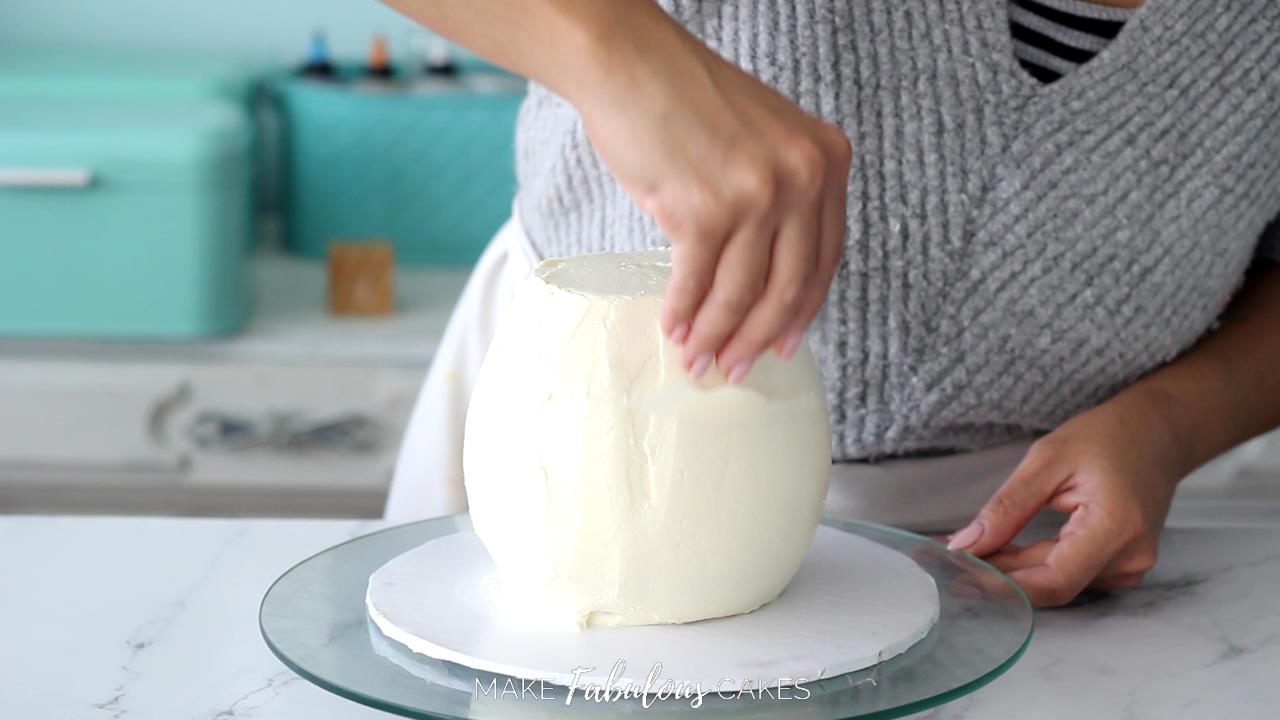 smoothing the frosting of the mushroom cake base with acetate